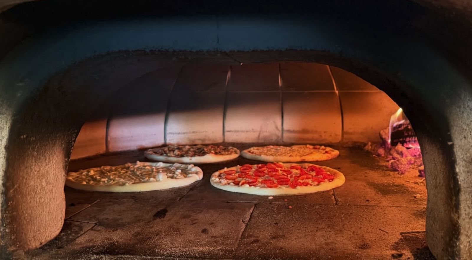 Four pizzas baking in Alpine Pizza's wood-fired oven